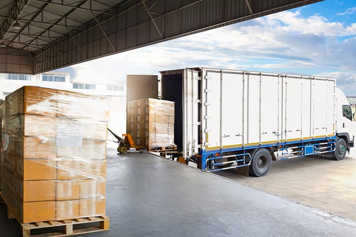 Warehouse loading dock with pallets and a truck backed up to the door